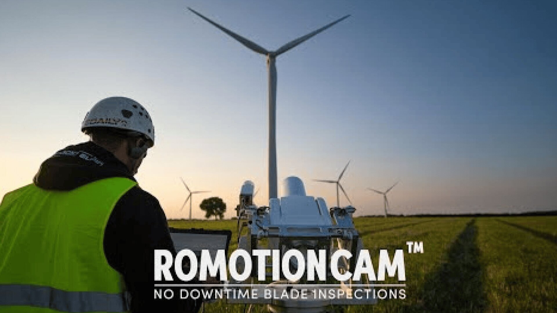 A person in a safety vest and helmet operates a tablet in a field with wind turbines at sunset; equipment and the text Romotioncam: No Downtime Blade Inspections are visible in the foreground.