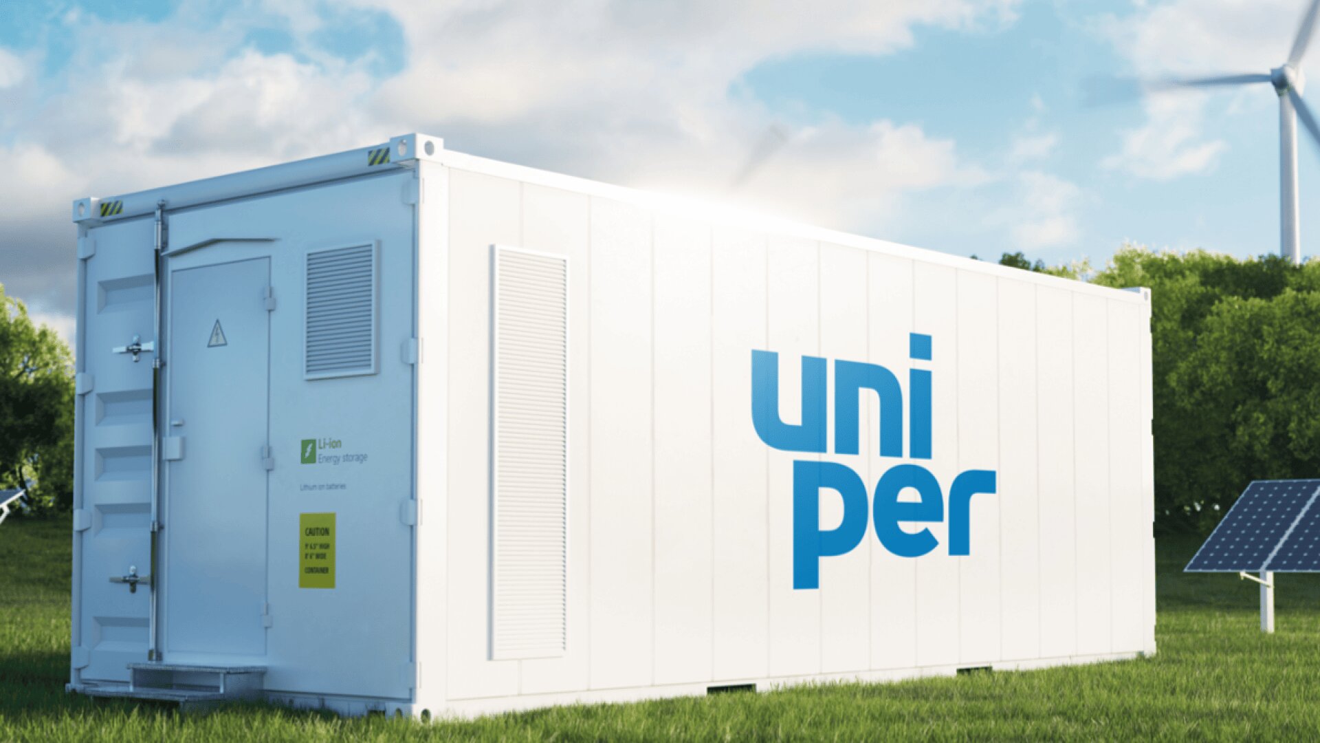 A white energy storage container with the blue uniper logo stands on grass near solar panels and wind turbines, with trees and a partly cloudy sky in the background.