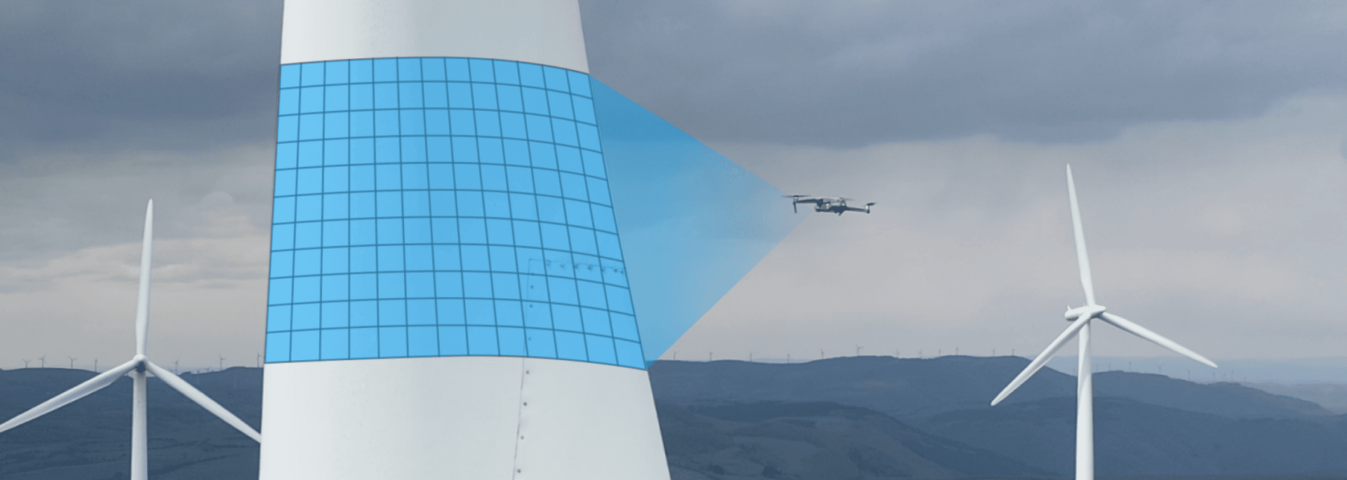 Eine Drohne inspiziert einen Turm einer Windkraftanlage, der durch ein blaues Gitter hervorgehoben wird. Zwei weitere Windturbinen stehen im Hintergrund vor einem bewölkten Himmel und entfernten Hügeln.