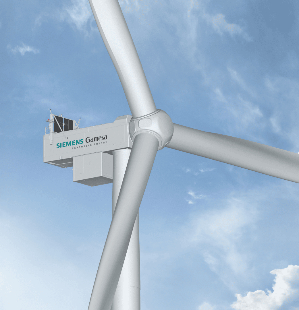 Close-up view of a Siemens Gamesa wind turbine against a blue sky with scattered clouds, showing the blades and nacelle with the company logo visible.