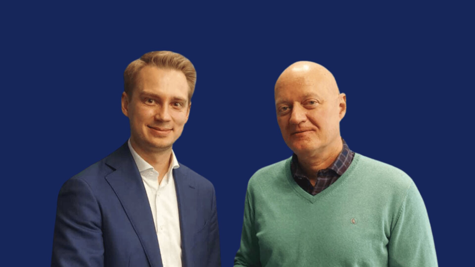 Zwei Männer stehen nebeneinander vor einem einfarbig blauen Hintergrund; einer trägt einen marineblauen Anzug und ein weißes Hemd, der andere einen grünen Pullover über einem karierten Hemd. Beide schauen in die Kamera und lächeln sanft.