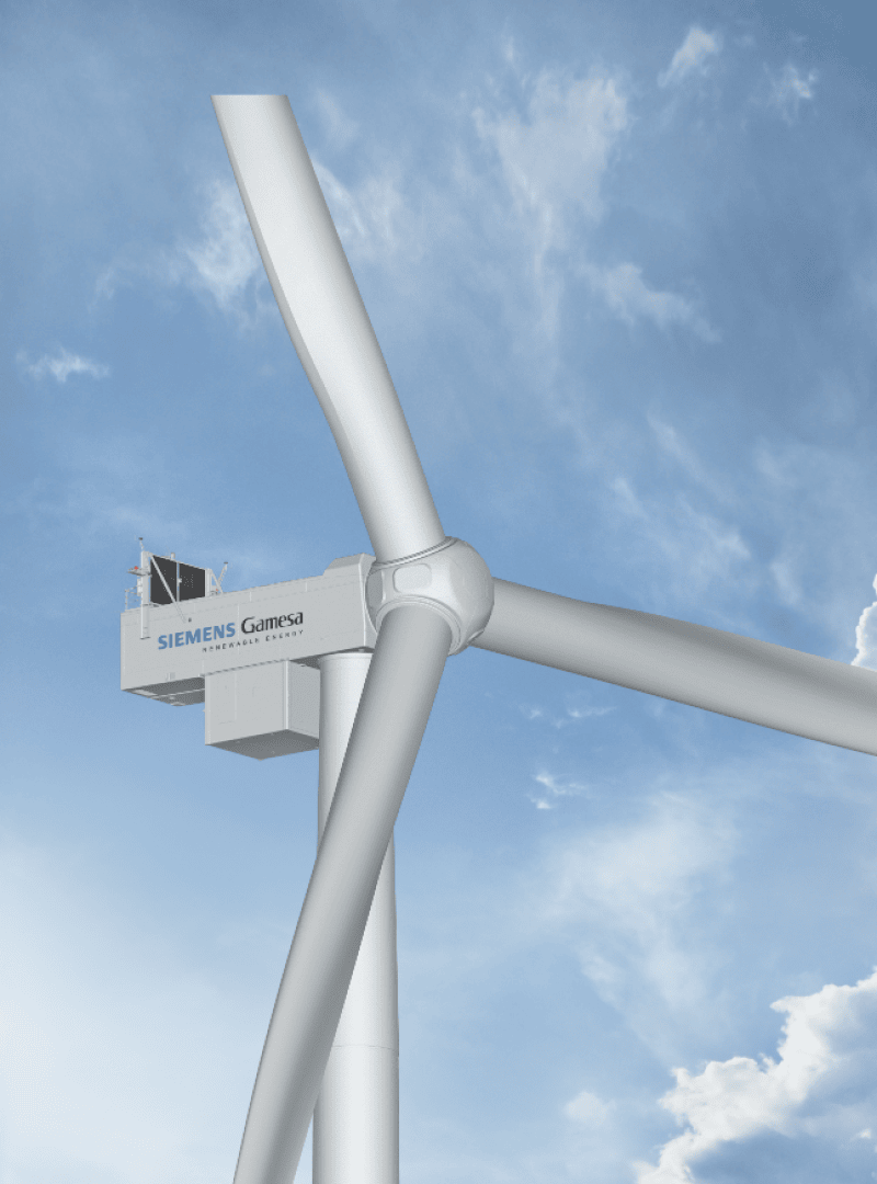Eine Siemens-Gamesa-Windturbine mit drei großen Flügeln erhebt sich vor einem teilweise bewölkten blauen Himmel.