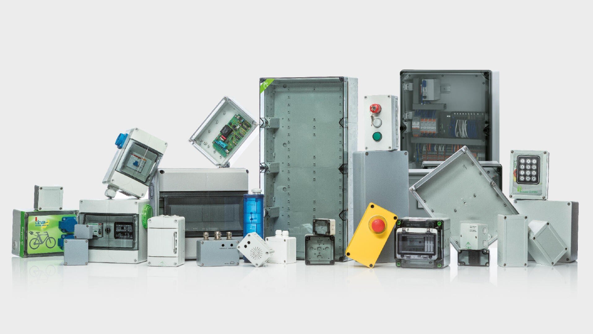 A large number of switch cabinets and distribution boxes of different sizes and shapes are arranged next to each other, some with visible cables, buttons and electronic components inside.
