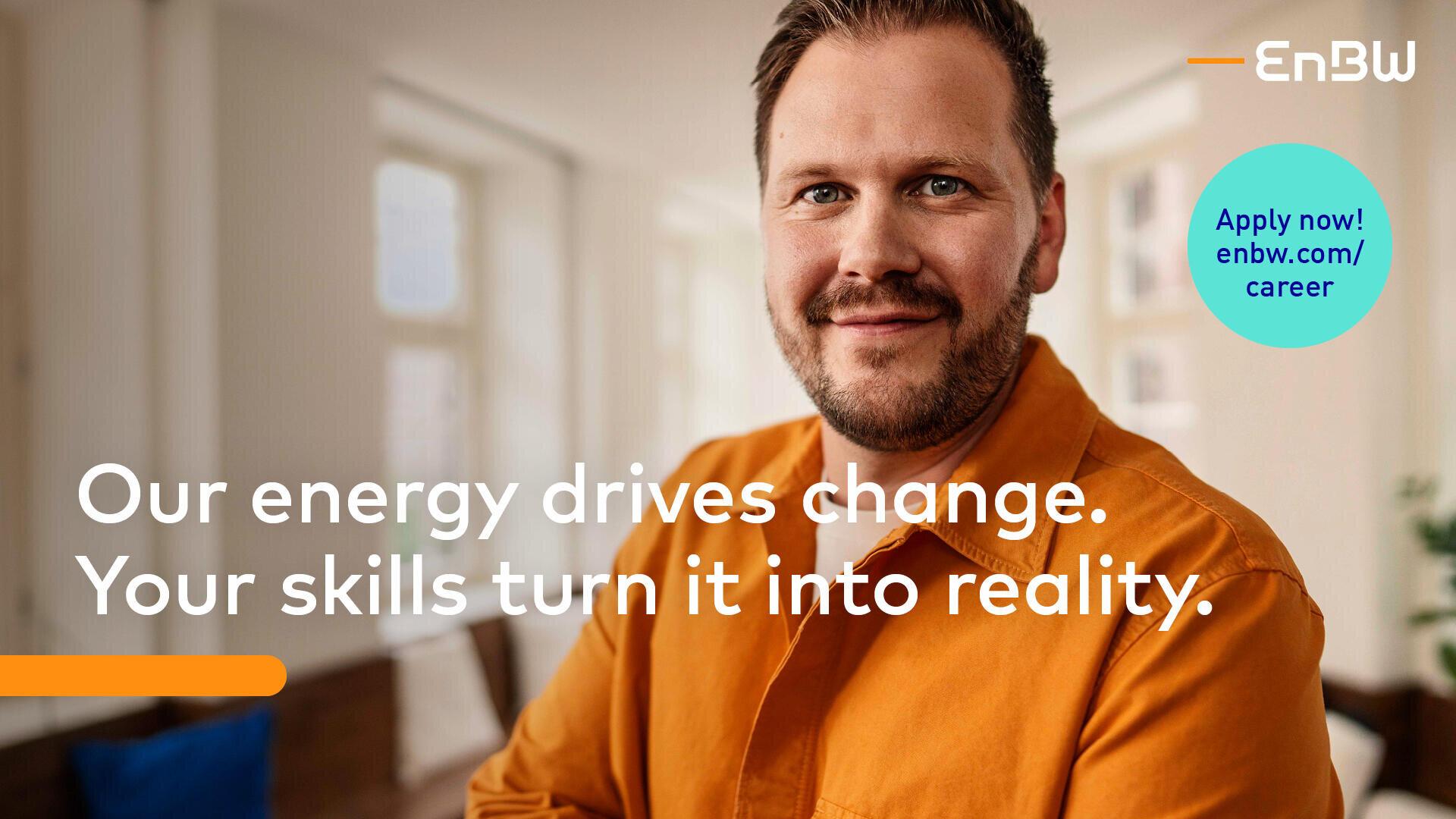 A smiling man in an orange shirt sits indoors. Text reads: Our energy drives change. Your skills turn it into reality. The EnBW logo and Apply now! enbw.com/career appear in the image.