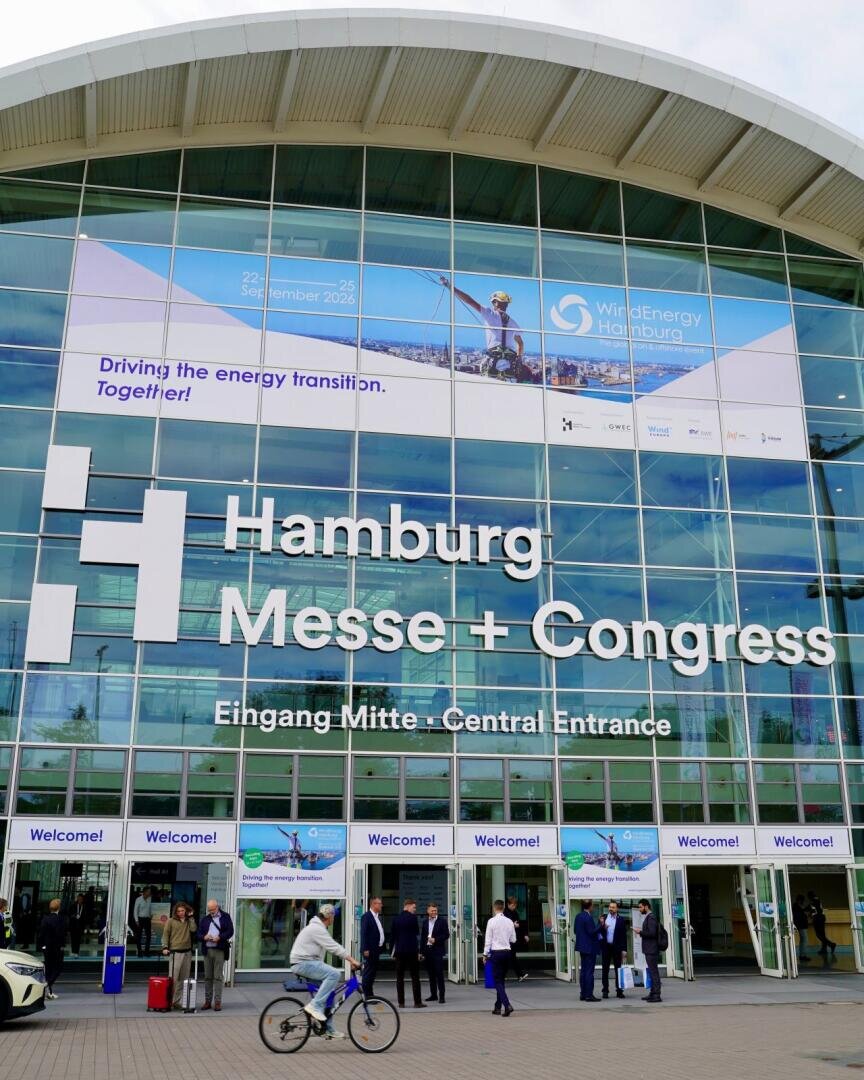 Der verglaste Eingangsbereich der Hamburg Messe + Congress mit einem großen Banner für die Veranstaltung WindEnergy Hamburg, die vom 22. bis 25. September 2026 stattfinden soll.