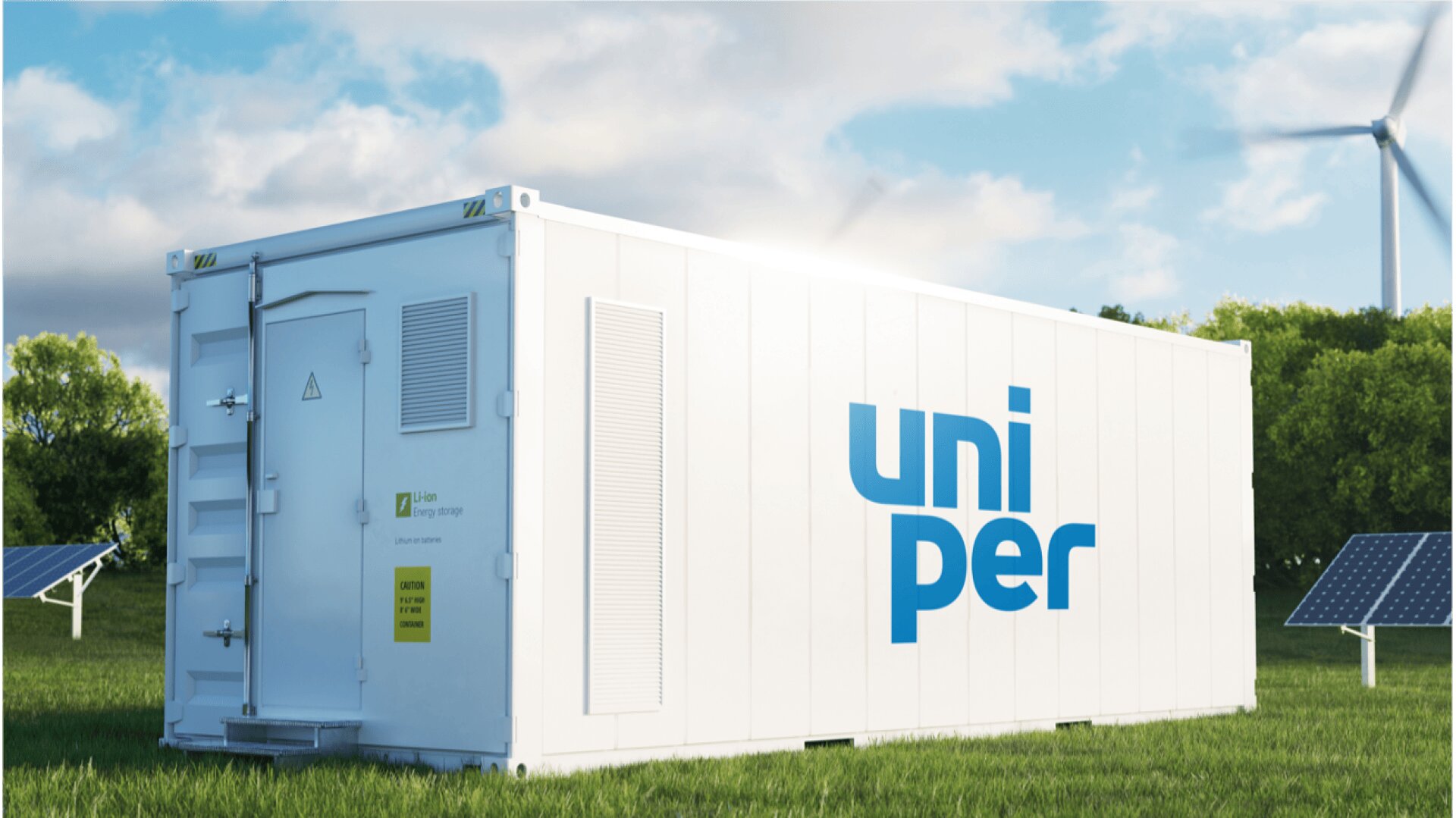 Ein weißer Container mit dem blauen uniper-Logo steht auf grünem Gras, umgeben von Sonnenkollektoren und Bäumen, mit einer Windkraftanlage im Hintergrund unter einem teilweise bewölkten Himmel.