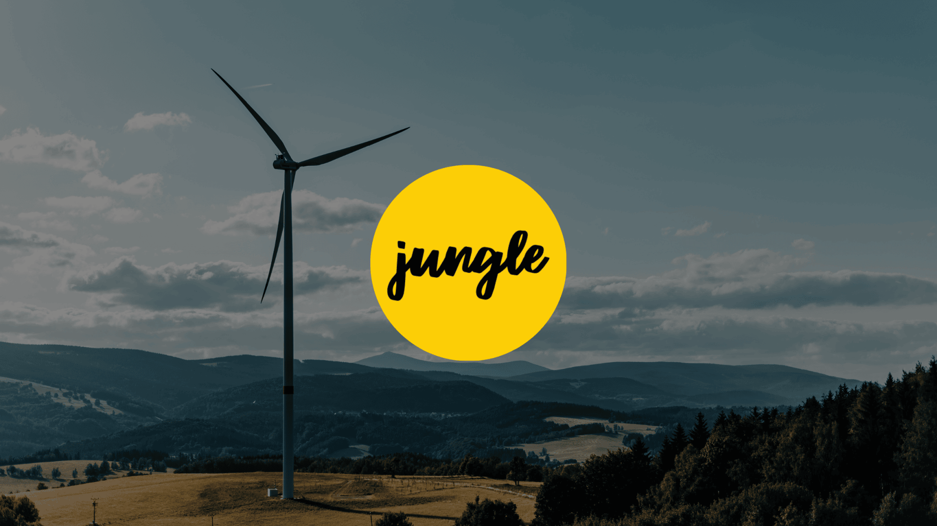 A wind turbine stands in a hilly landscape under a cloudy sky. A large yellow circle with the word jungle in black script is centered over the image.