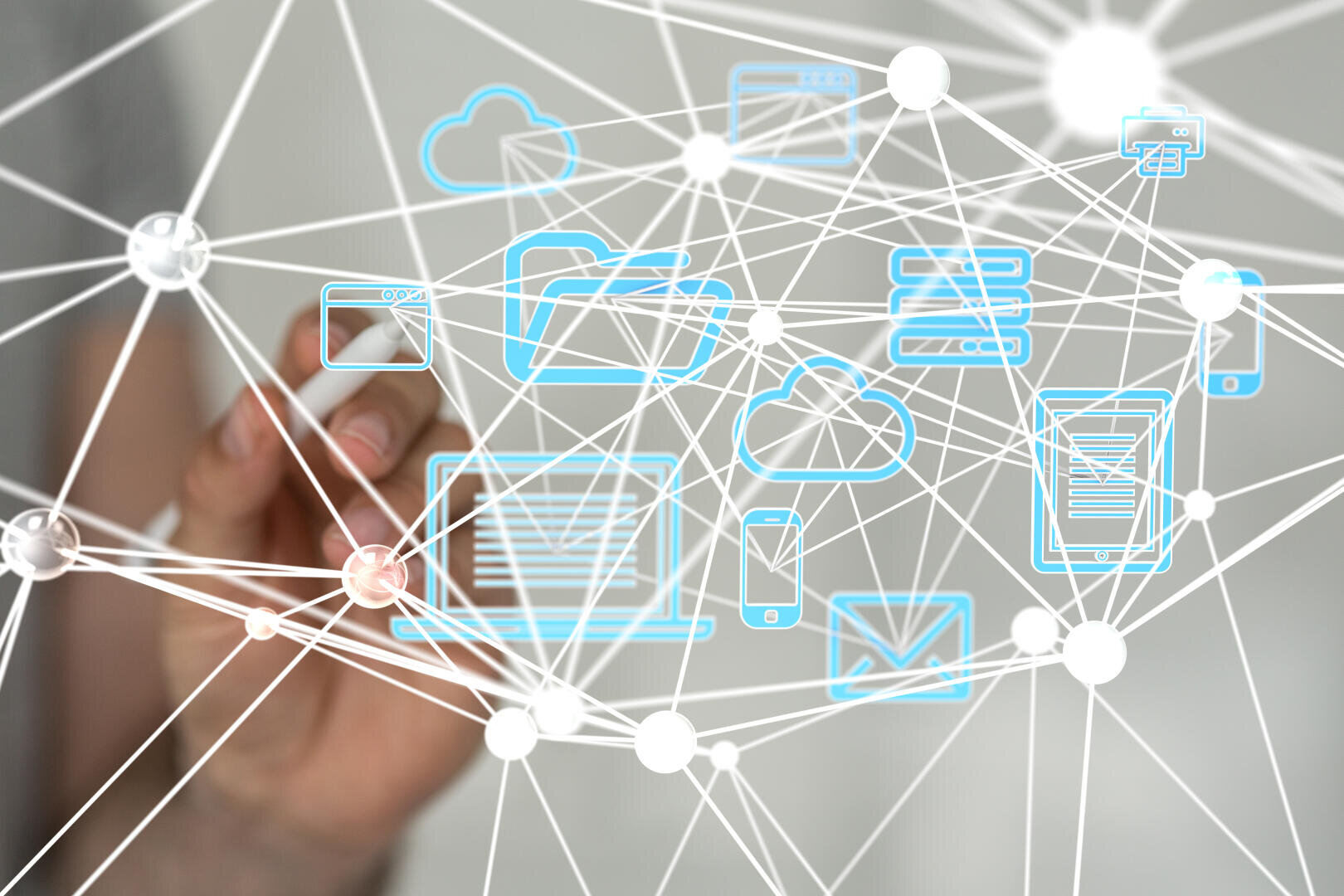 A person's hand touches a transparent screen on which interconnected digital icons can be seen, including a laptop, smartphone, cloud and email, symbolizing digital connectivity and network communication.