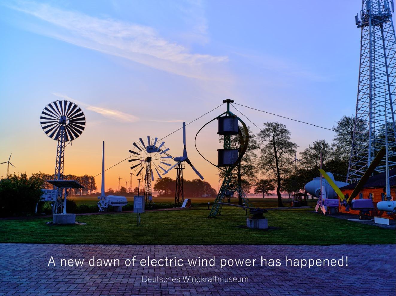 Verschiedene Arten von Windturbinen stehen in einer Freiluftausstellung bei Sonnenaufgang, mit bunten Wolken am Himmel. Der Text lautet: "Eine neue Ära der elektrischen Windenergie ist angebrochen! Deutsches Windkraftmuseum.".