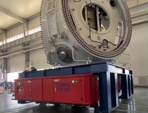 In a spacious, well-lit factory with high ceilings, a large industrial machine component is mounted on a red automated guided vehicle (AGV) labeled LANYU.